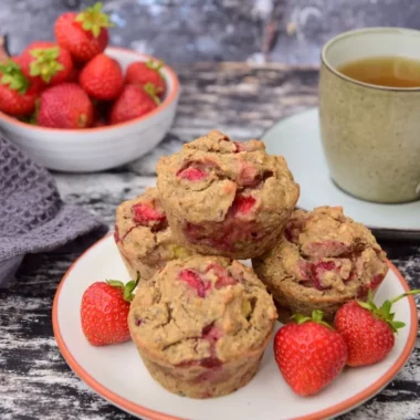 Gluten-free strawberry muffins on a plate with fresh strawberries.