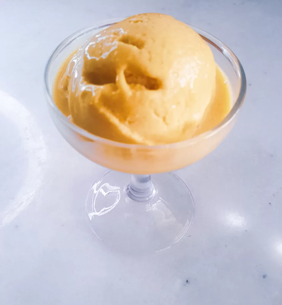 Sugar-free dairy-free mango Ice cream in a dessert glass.