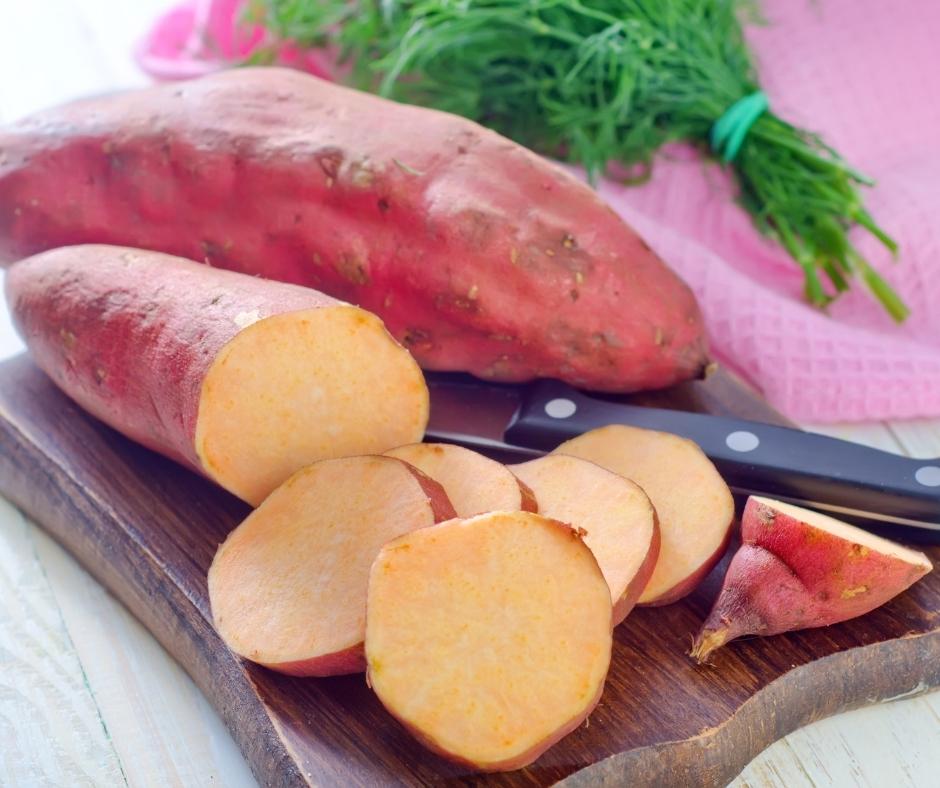 Orange sweet potatoes on a cutting board.