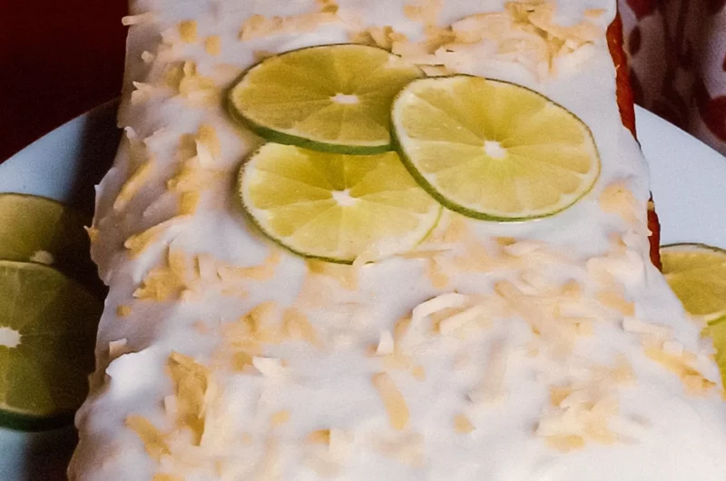 Coconut lime cake on a plate garnished with lime slices and toasted coconut.