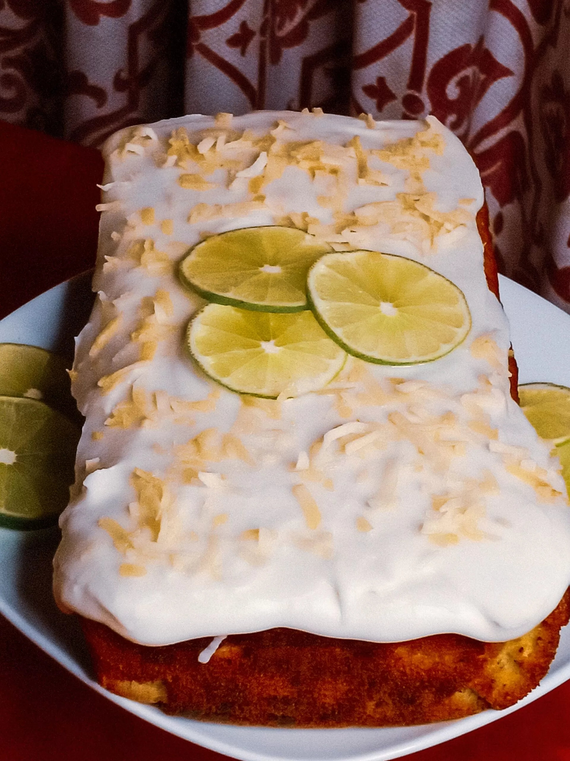 Coconut lime cake on a plate garnished with lime slices and toasted coconut.
