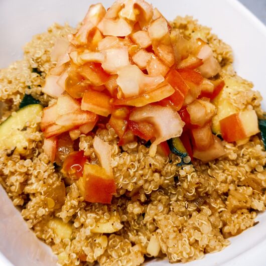 Quinoa zucchini lime salad in a bowl garnished with diced tomatoes.
