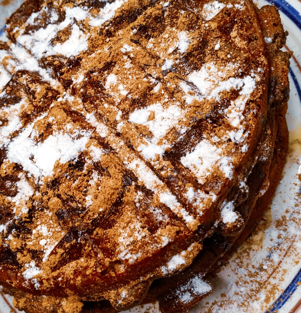 Keto chocolate protein waffles garnished with cacao powder and sugar-free powdered sugar