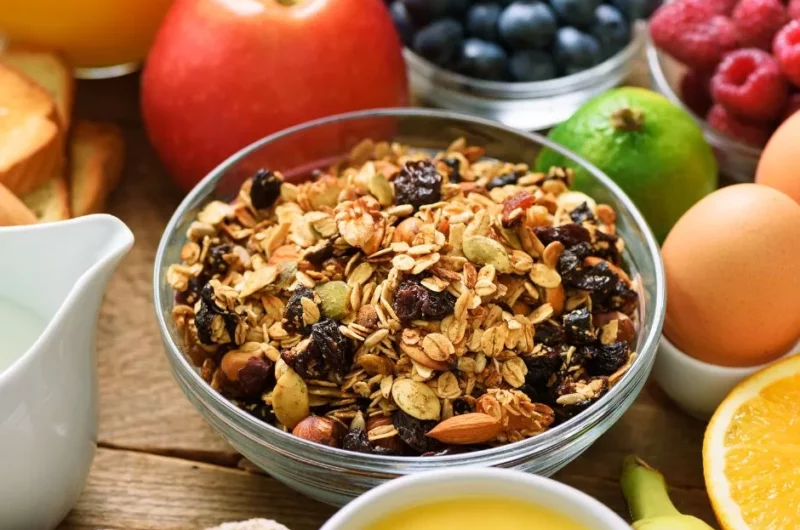 Granola cereal with nuts and seeds on a breakfast table with bread and fresh fruit
