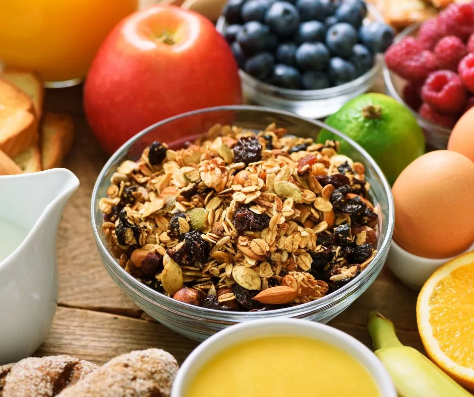Granola cereal with nuts and seeds on a breakfast table with bread and fresh fruit