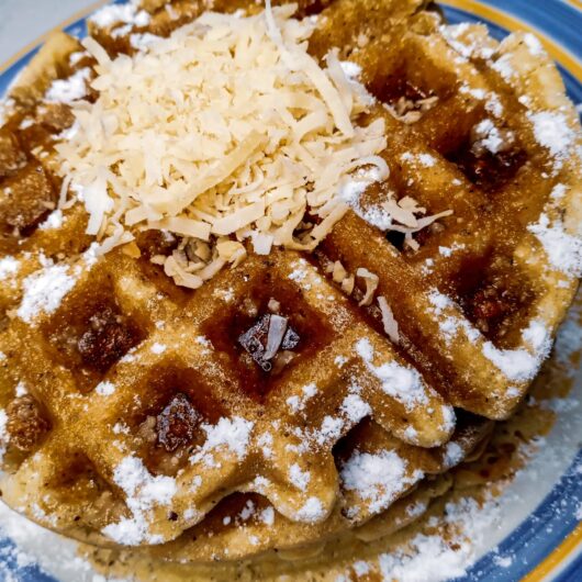 Toasted coconut waffles on a plate topped with toasted coconut and sugar-free sweetener