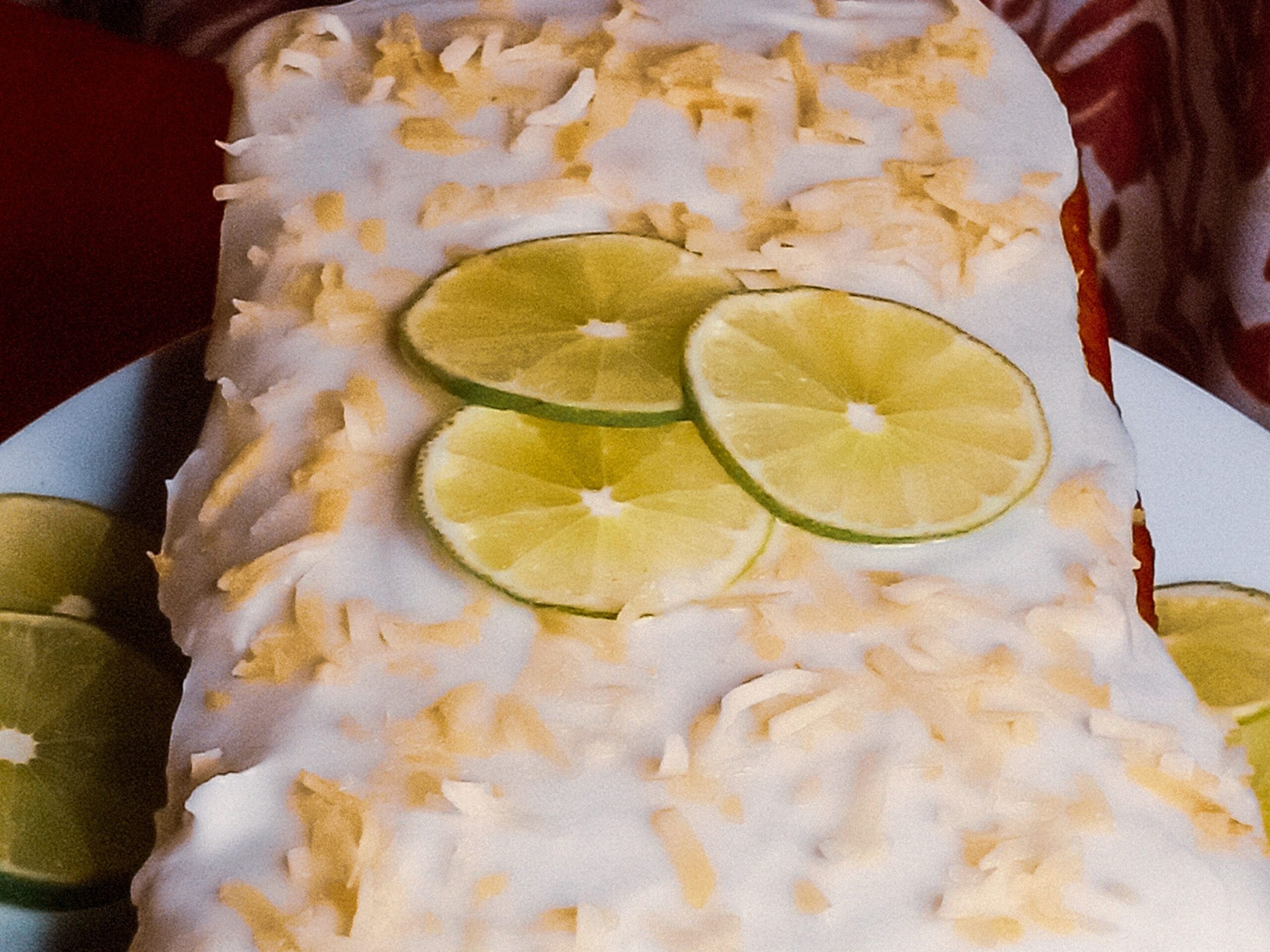Coconut lime cake on a plate garnished with lime slices and toasted coconut.