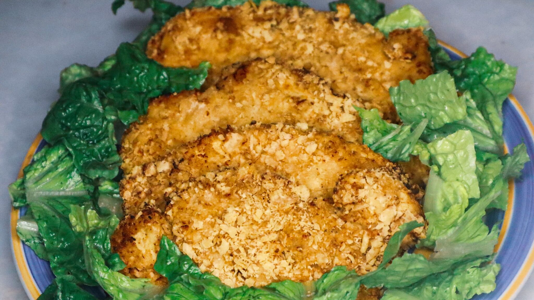 Air fryer sour cream and onion chicken on a plate garnished with Romaine lettuce.