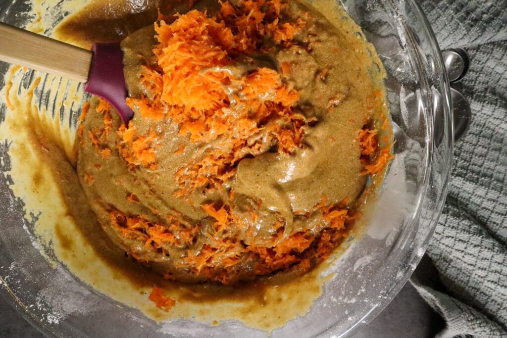 Carrots being mixed into paleo carrot cake muffin batter.