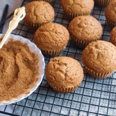 Gluten-free apple butter muffins on a cooling rack with chai spice mix in a small bowl.