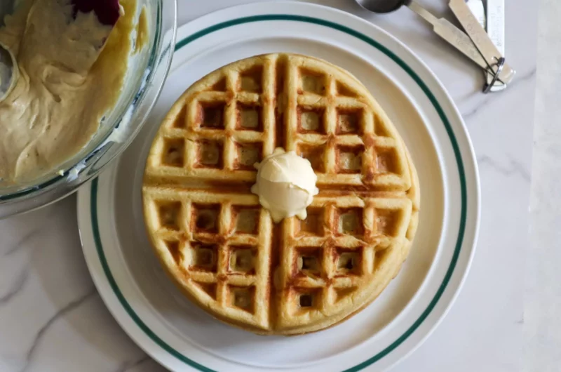 Gluten-free waffles on a plate topped with butter.