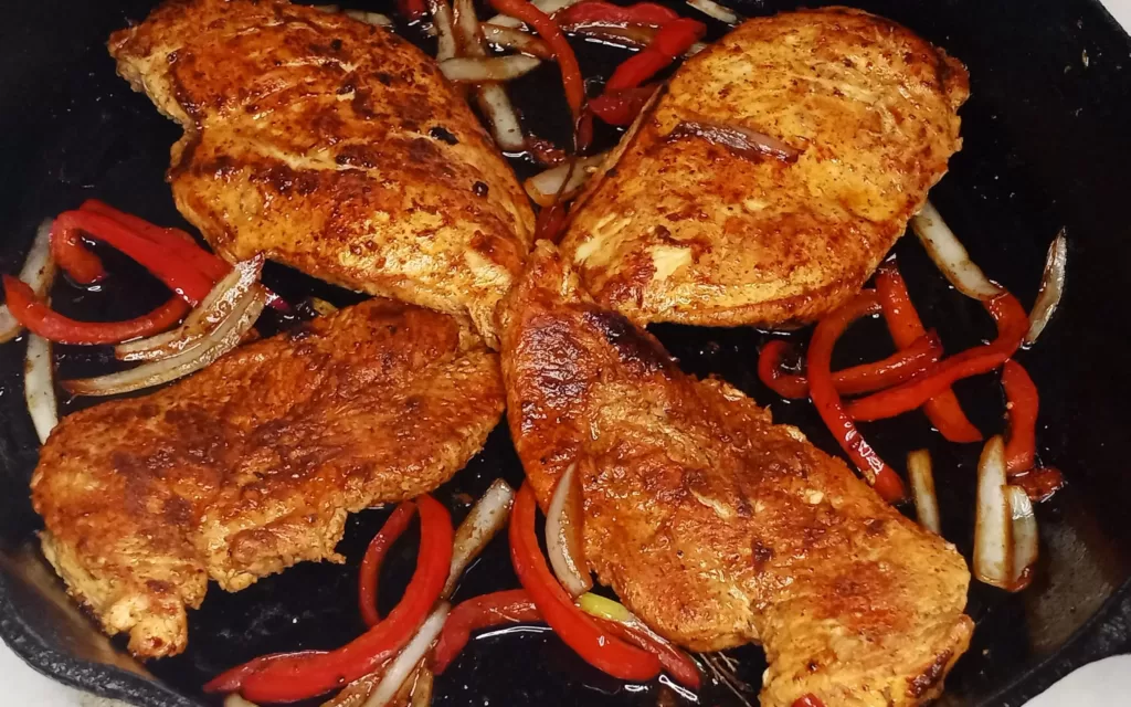 smoked paprika chicken in a cast-iron skillet with onions and peppers
