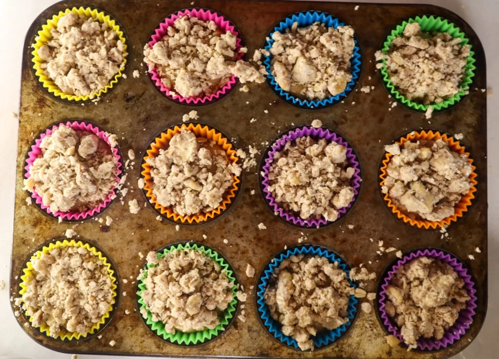 Unbaked maple crunch muffins in a muffin pan.