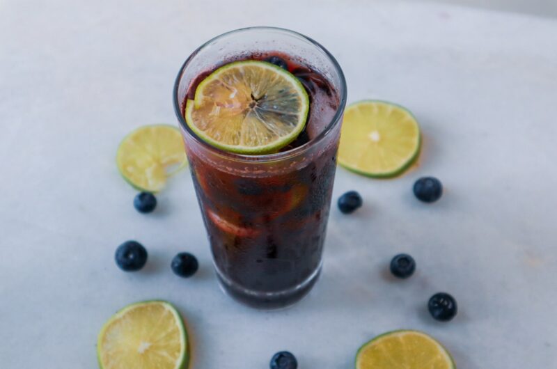 Blueberry Lime Refresher in a glass garnished with lime slices and blueberries.