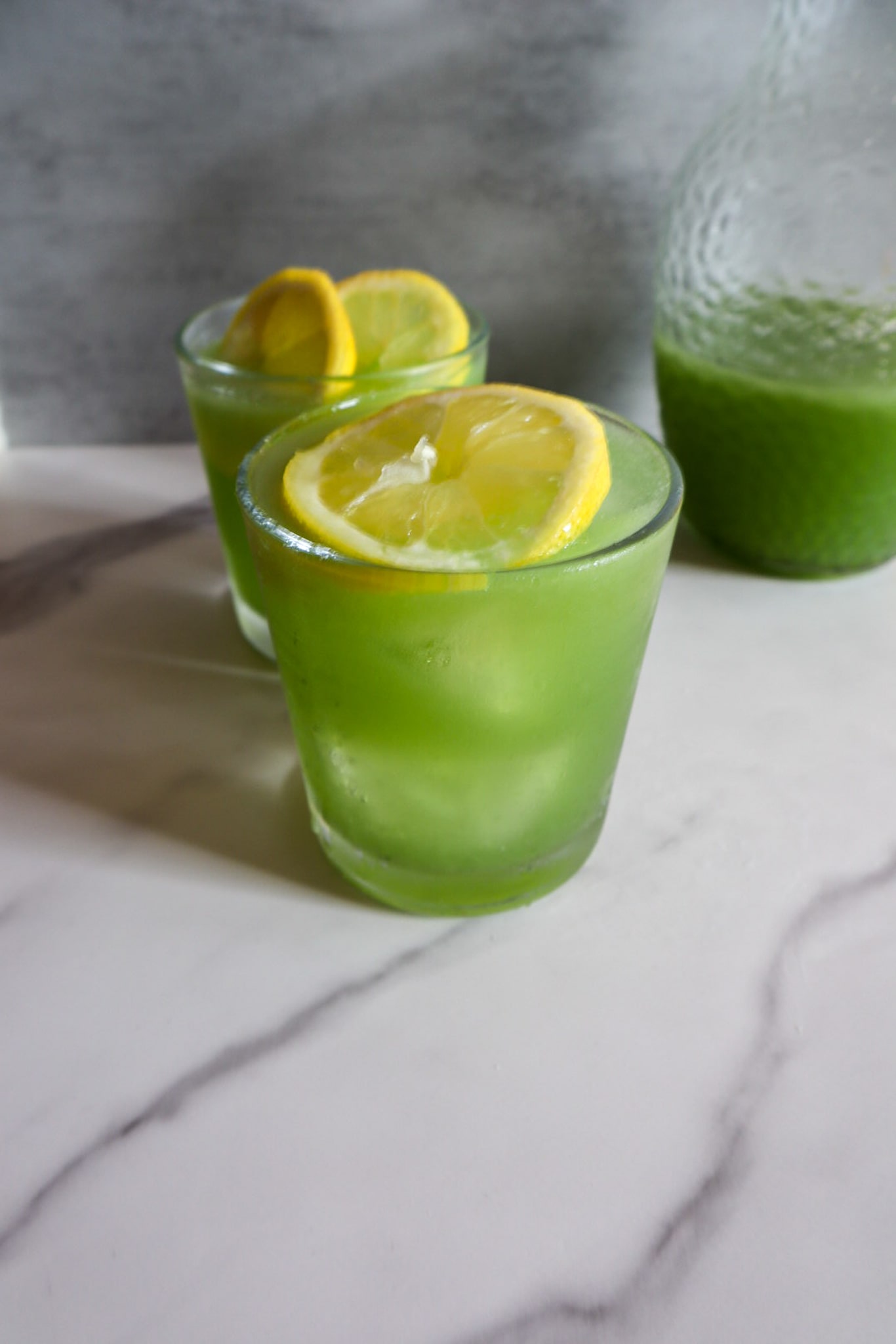 Refreshing coconut cucumber water in 2 glasses garnished with lime.