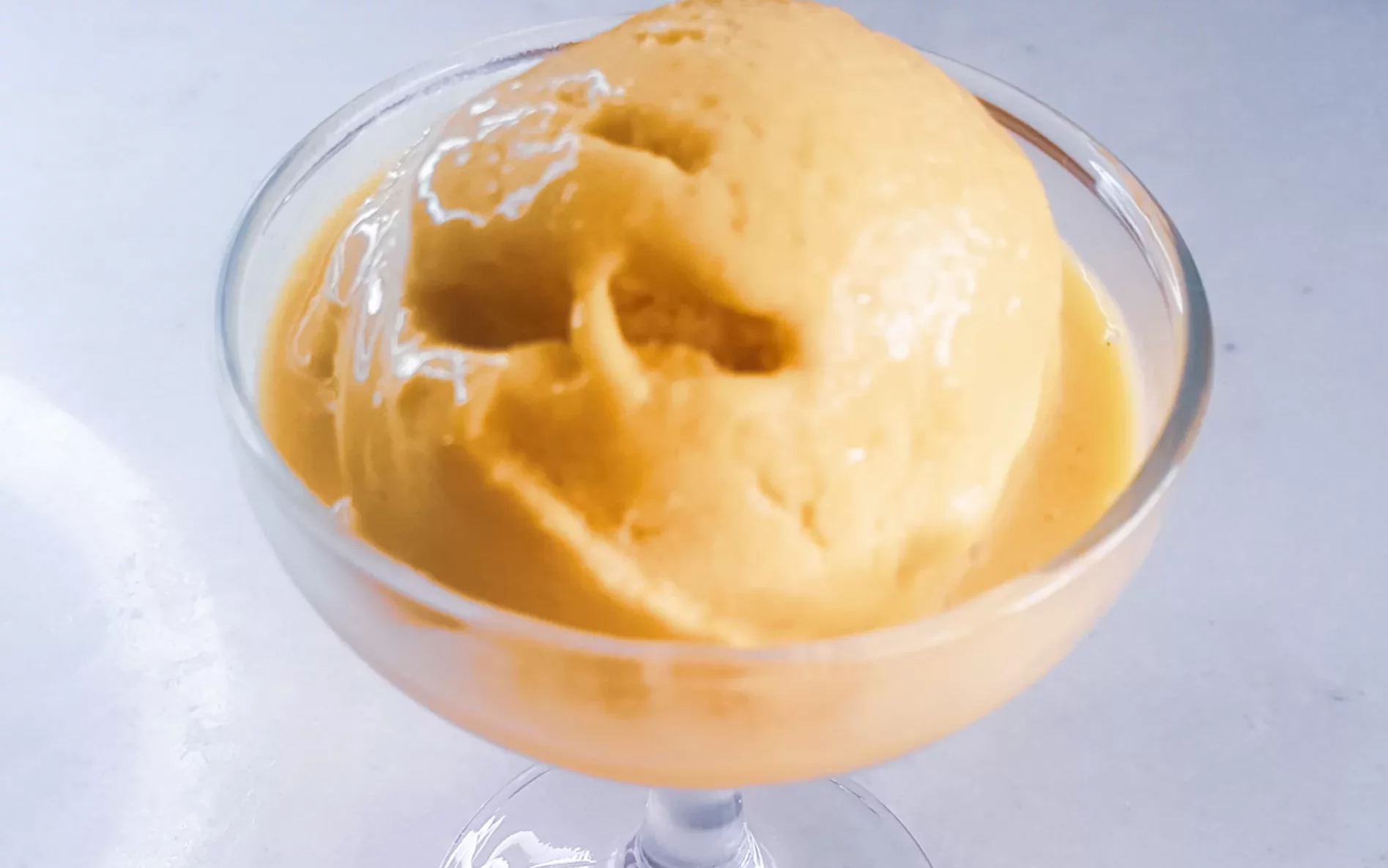 Sugar-free dairy-free mango Ice cream in a dessert glass.