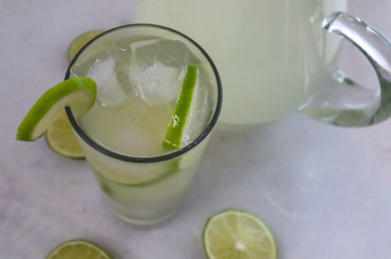 A glass of switcha (limeade) garnished with fresh lime slices.