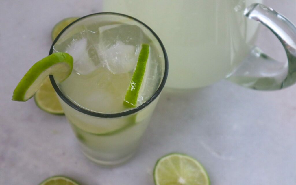 A glass of switcha (limeade) garnished with fresh lime slices.