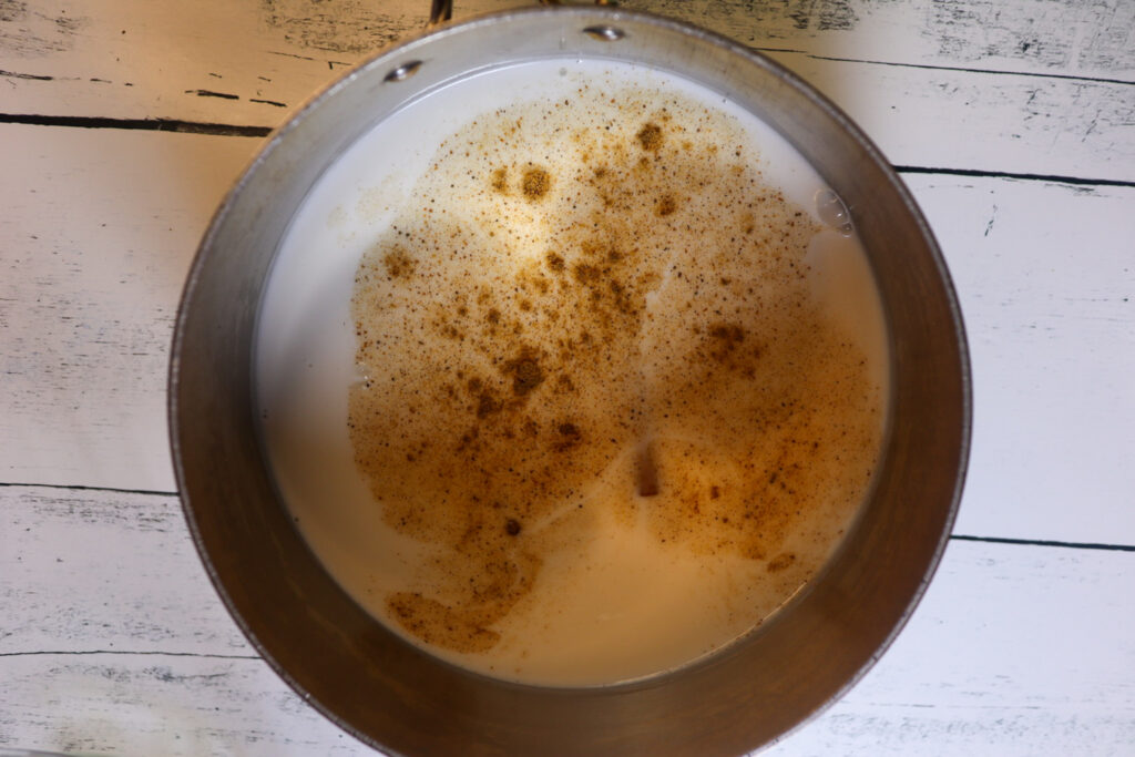 Heating coconut milk and spices in a pot. 