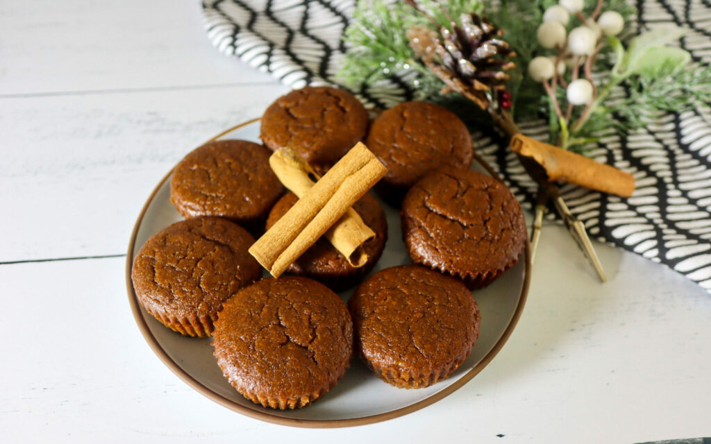 Gluten-free gingerbread muffins on a plate garnished with cinnamon sticks.