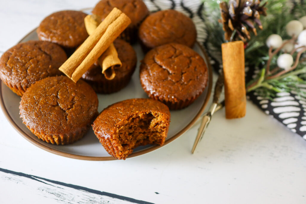 Gluten-free gingerbread muffins on a plate garnished with cinnamon sticks.