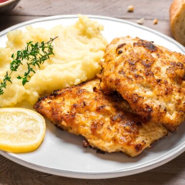 Mashed potatoes with fried chicken cutlets and lemon slices.