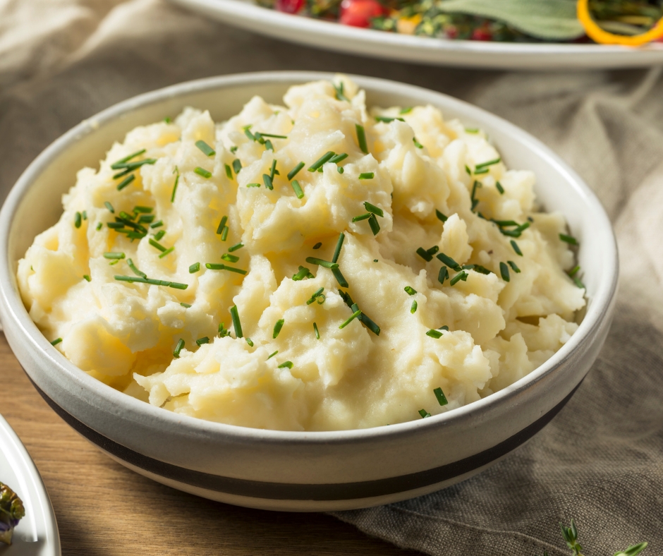 Creamy mashed potatoes in a bowl garnished with fresh chives.