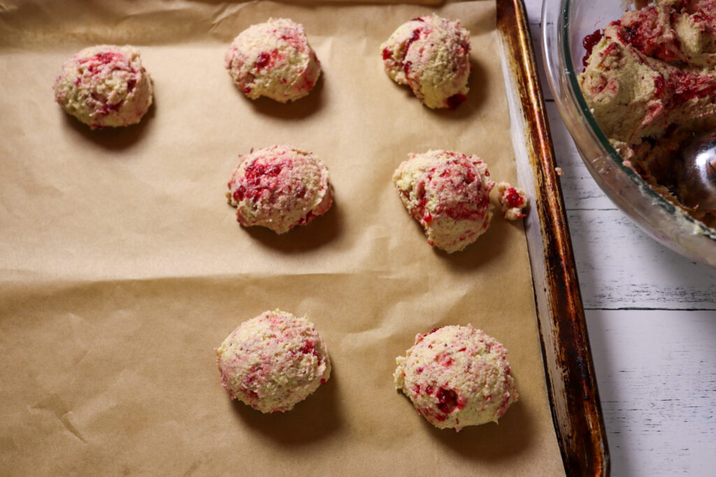 Scooping the cranberry jam sugar cookies on a parchment-lined baking sheet.