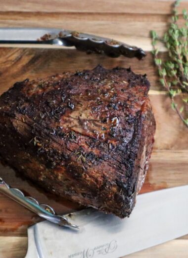 Air fryer roast beef on a cutting board garnished with fresh thyme.