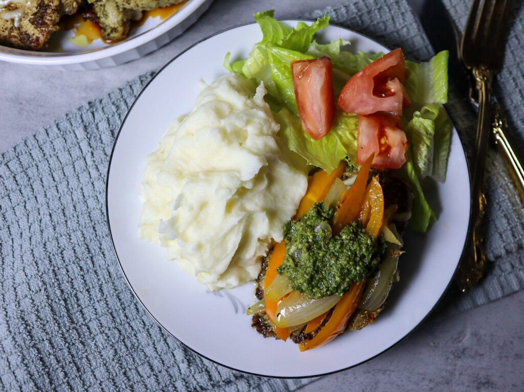 Cheesy pesto chicken served with mashed potatoes and a side salad.