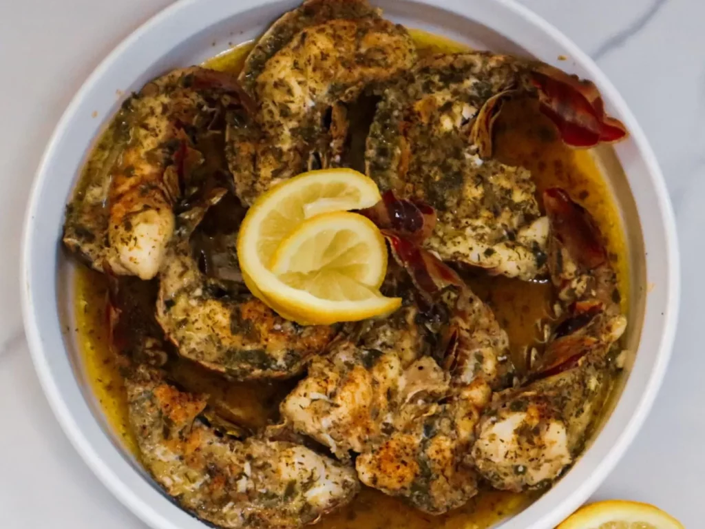 Baked garlic butter lobster tails in a baking dish garnished with lemon slices.
