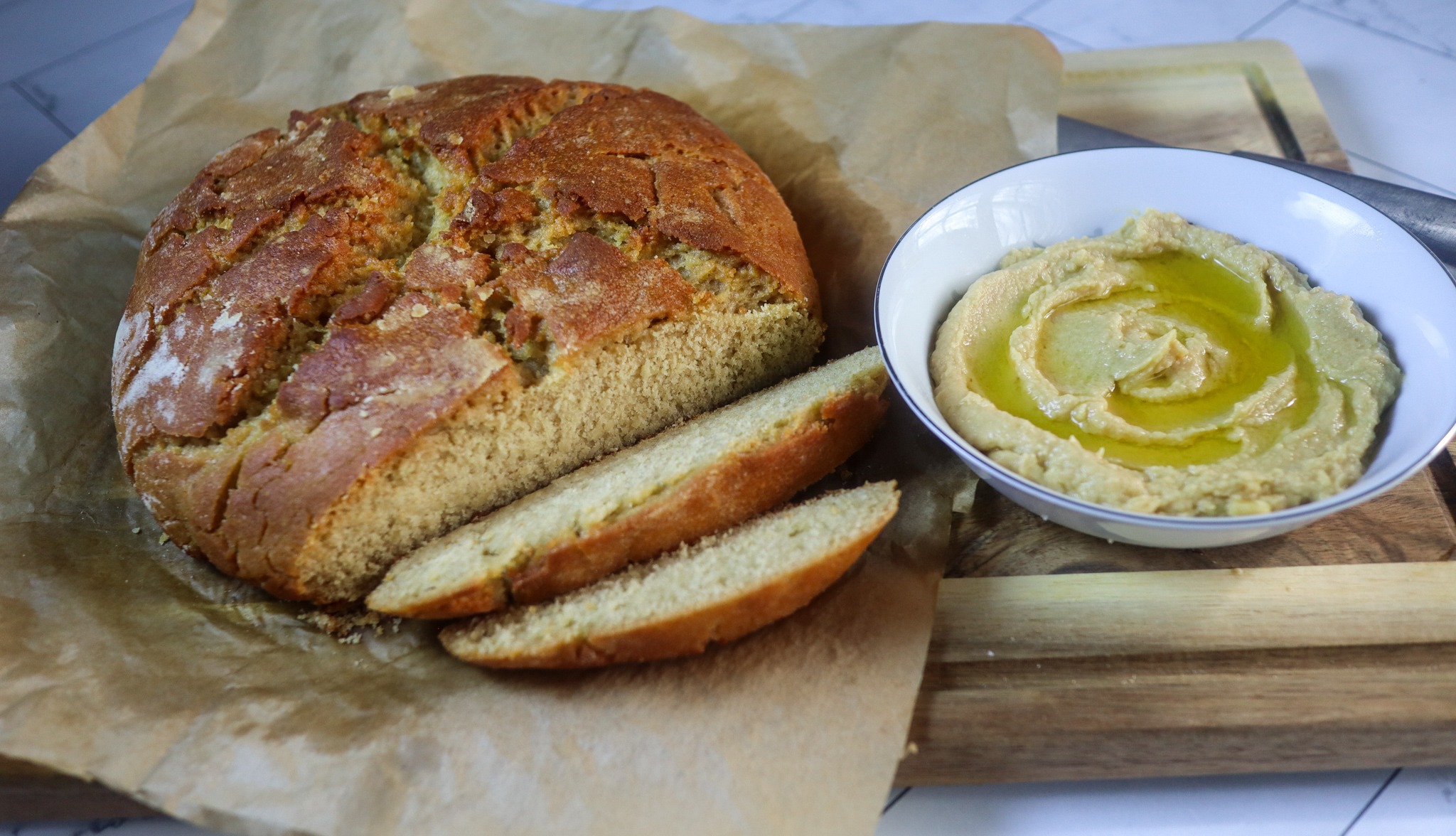 Gluten-free hummus bread and homemade hummus on a sheet of parchment paper.