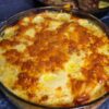 Scalloped potatoes with cranberry-glazed pork chops in the background.