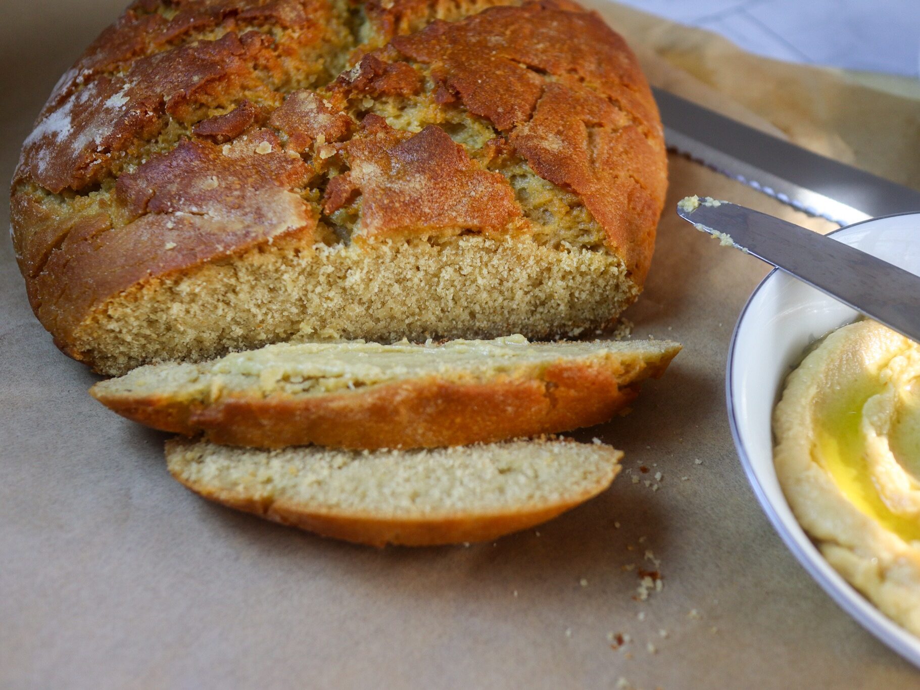Gluten-free hummus bread and homemade hummus on a sheet of parchment paper.