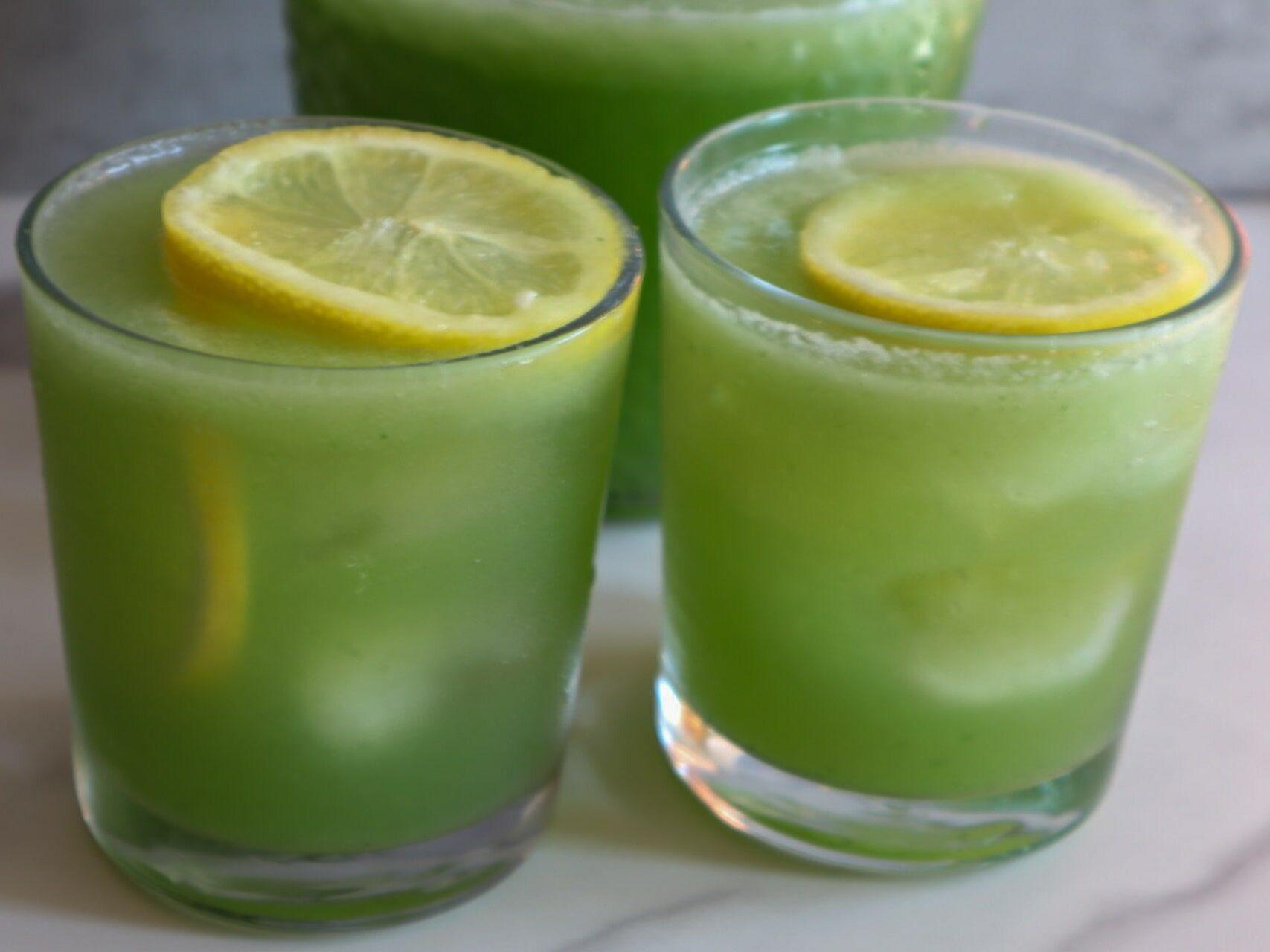 Refreshing coconut cucumber water in 2 glasses garnished with lime.