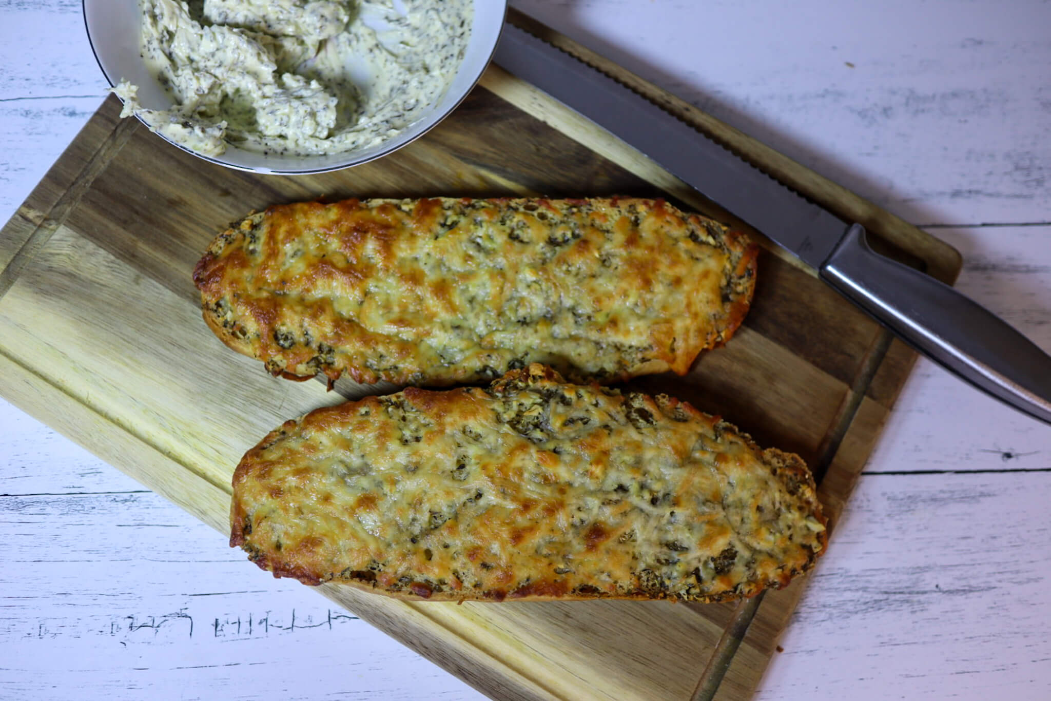 Cheesy garlic bread on a cutting board with garlic butter.